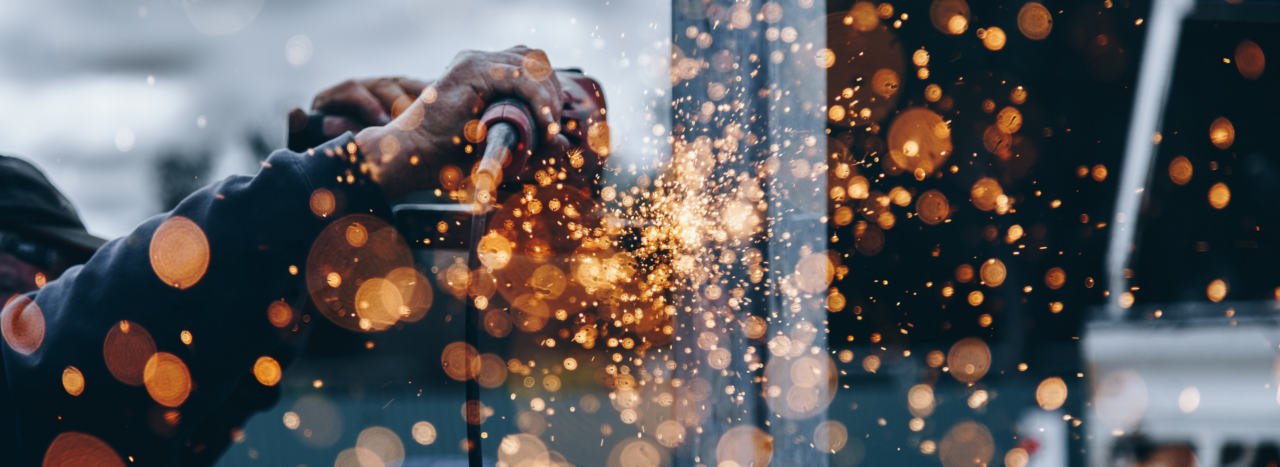 Hand holding manufacturing machine with orange sparks